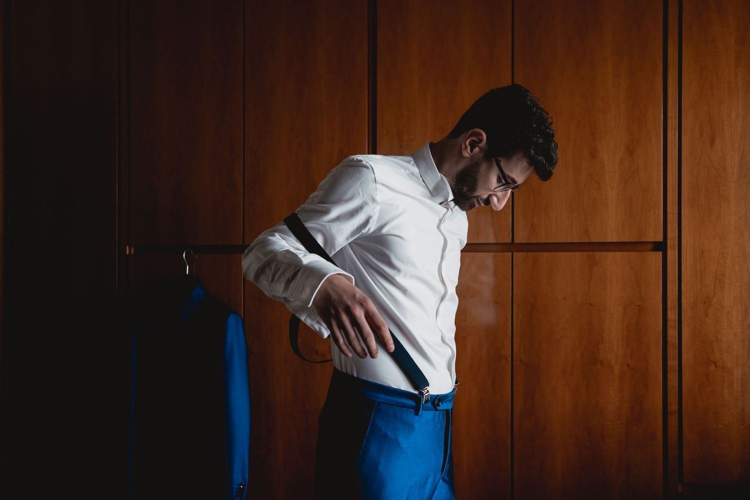 Silhouette against wooden paneling wearing crisp white shirt and blue pants.