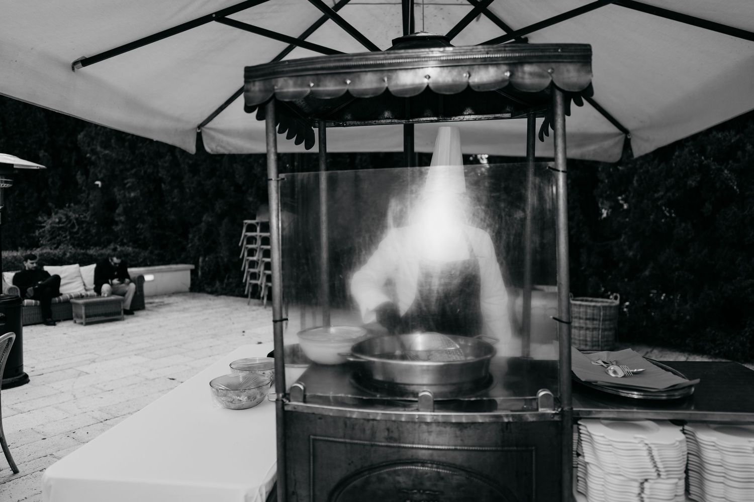 Black and white photo of a flaming outdoor cooking station at an evening wedding reception.