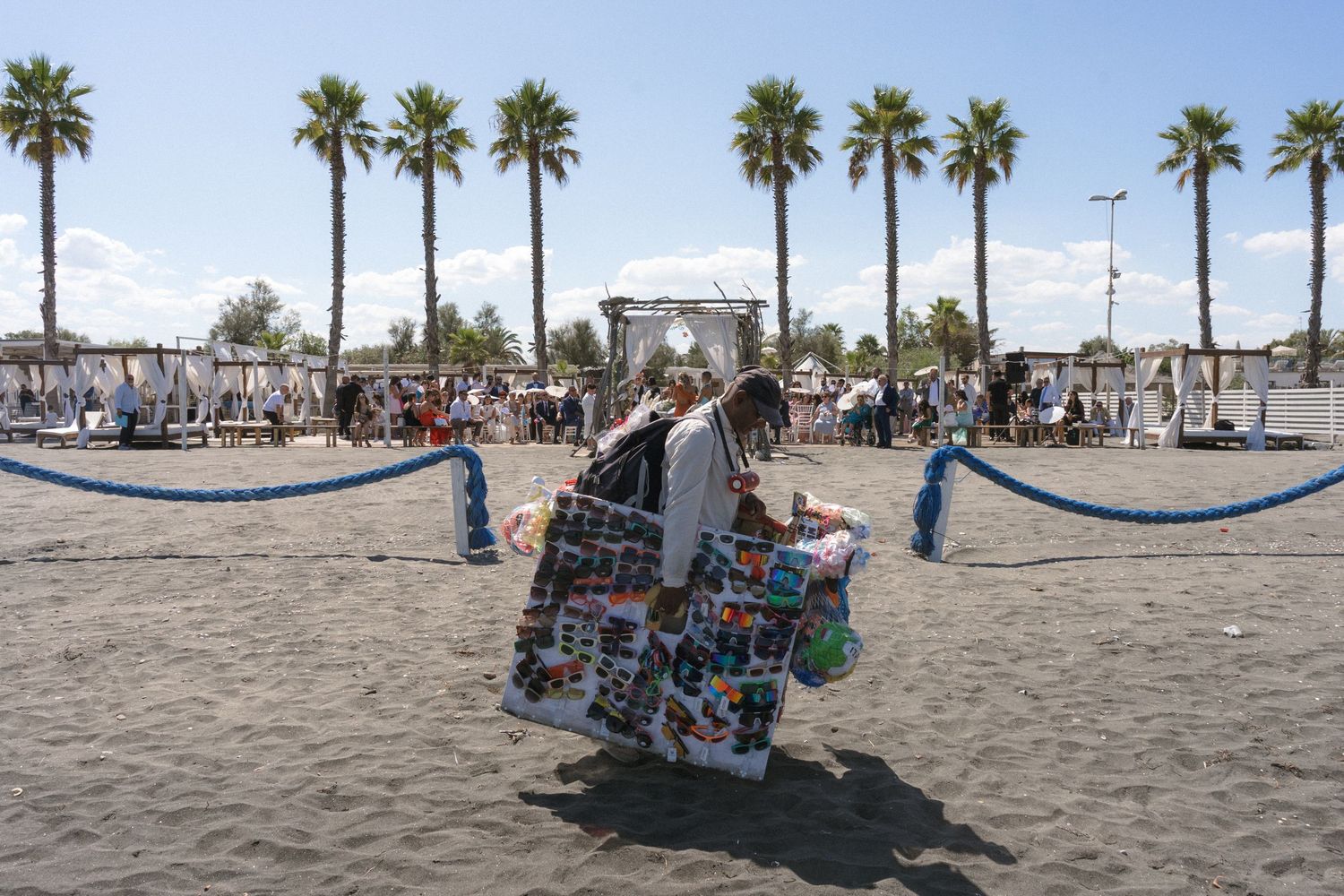 Palm tree lined beach with scattered beach chairs and umbrellas on a sunny day.