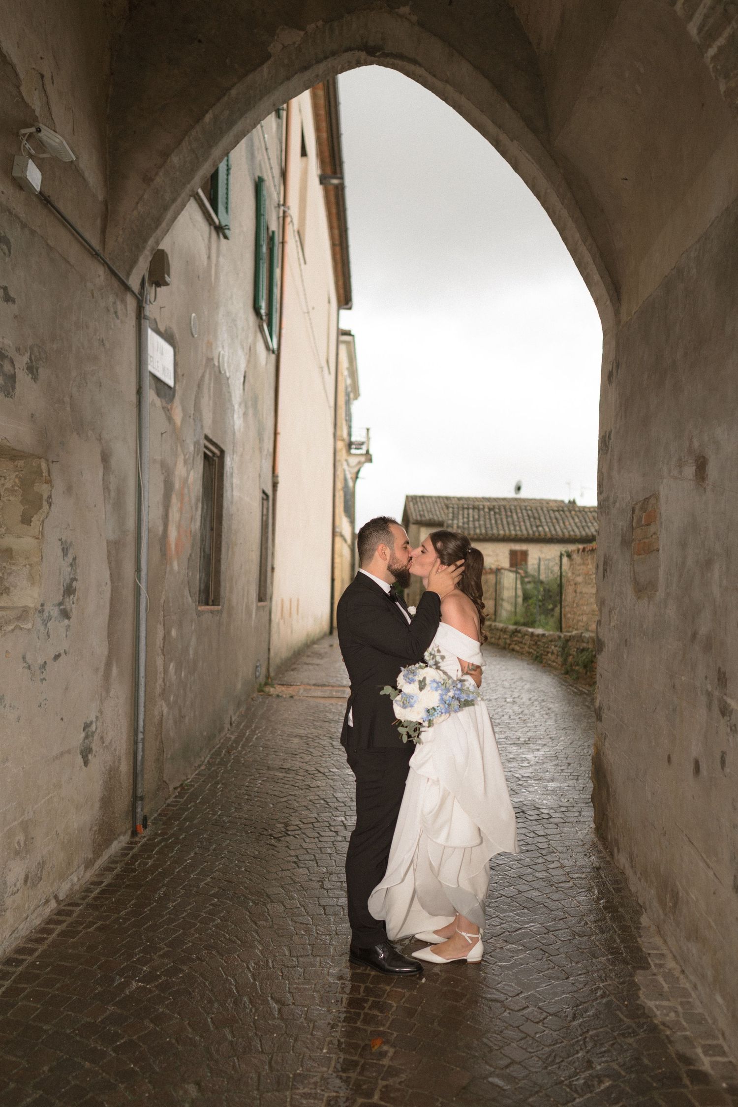 Romantic moments captured under stone archways in an old European village setting.
