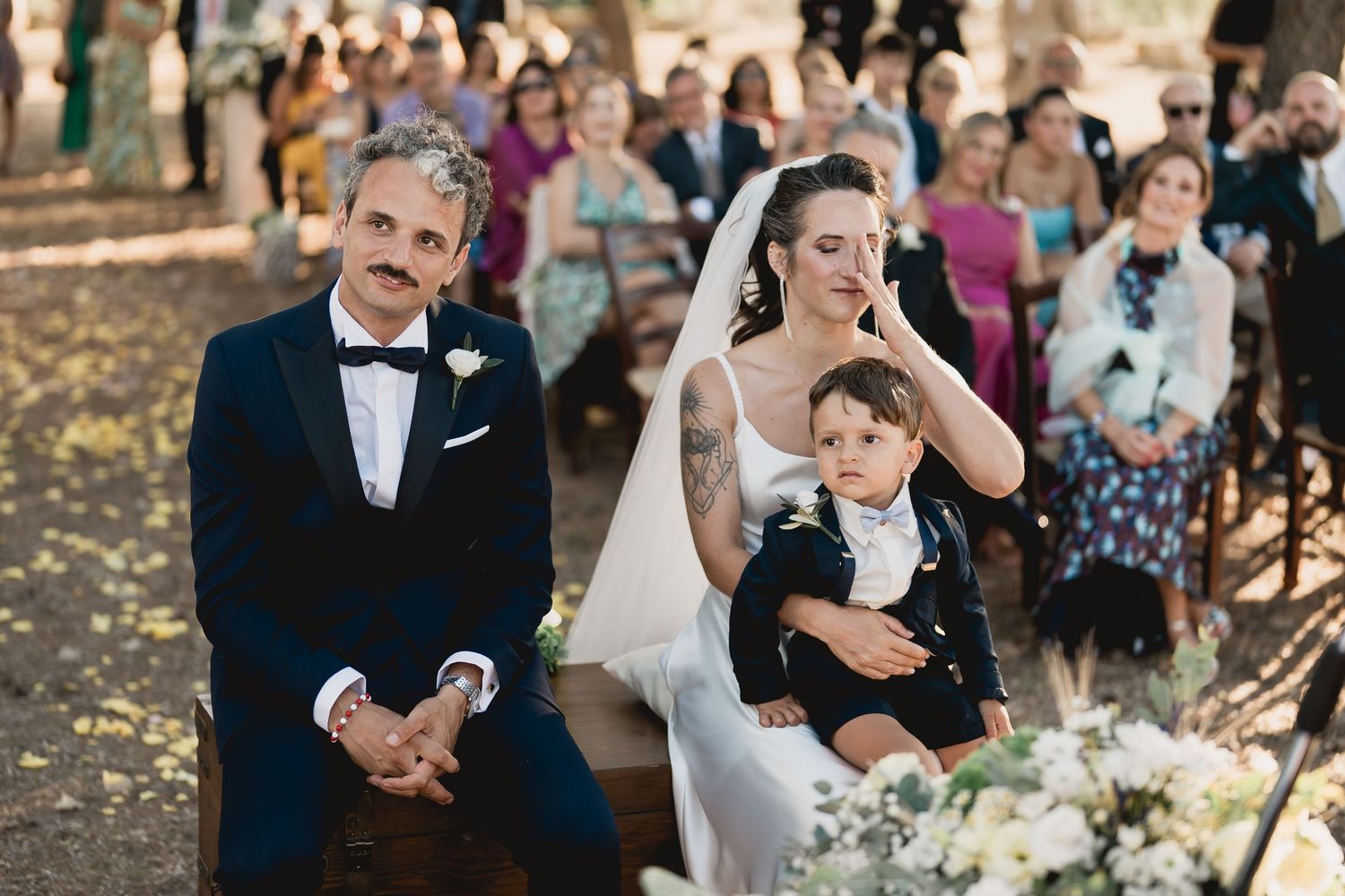 An emotional outdoor wedding ceremony scene with guests gathered to witness the special moment.