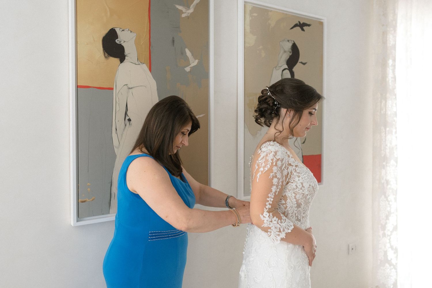 Wedding preparation scene in a bright interior room with artwork on the walls.