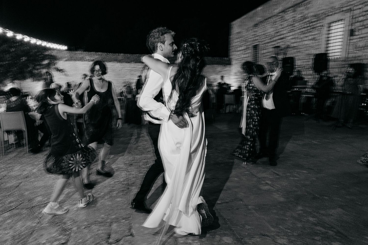 Black and white photo of couples dancing at an outdoor evening wedding reception.