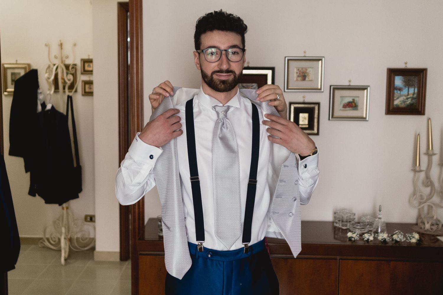 Formal attire featuring white shirt, blue suspenders and light grey tie.