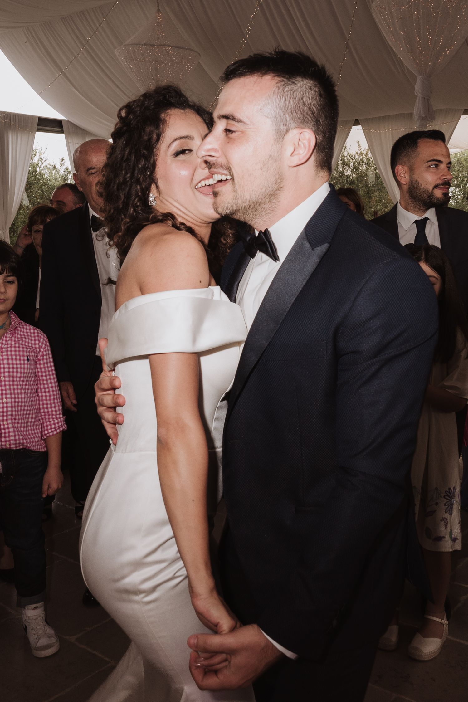Romantic moment shared between newlyweds during their wedding reception under a white tent.