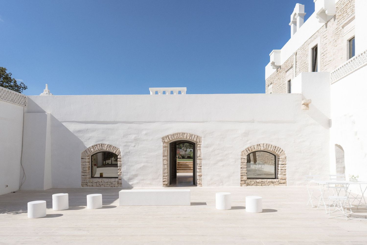 Whitewashed wedding venue courtyard with arched stone windows under a clear blue sky.