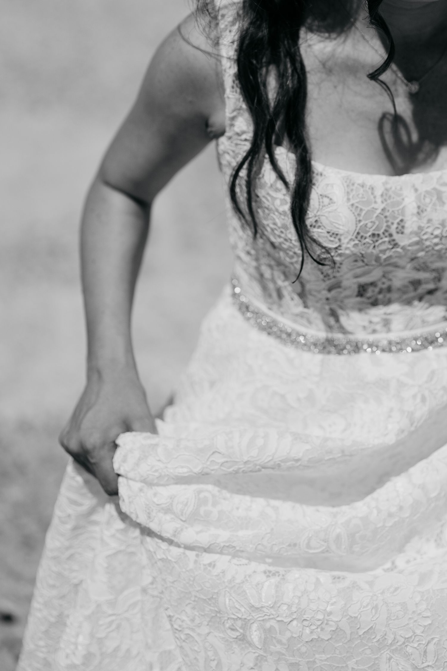 Black and white detail shot of a lace wedding dress with intricate embroidery details.