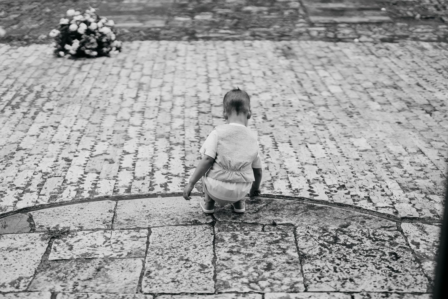 Black and white photograph of cobblestone street with people walking in the distance.