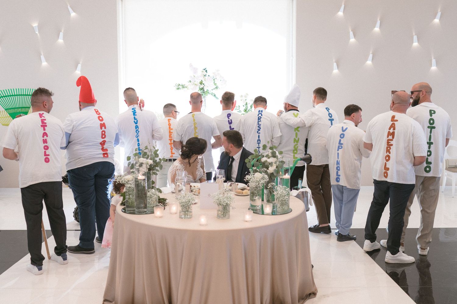 Modern white reception hall with guests mingling around elegantly decorated tables.