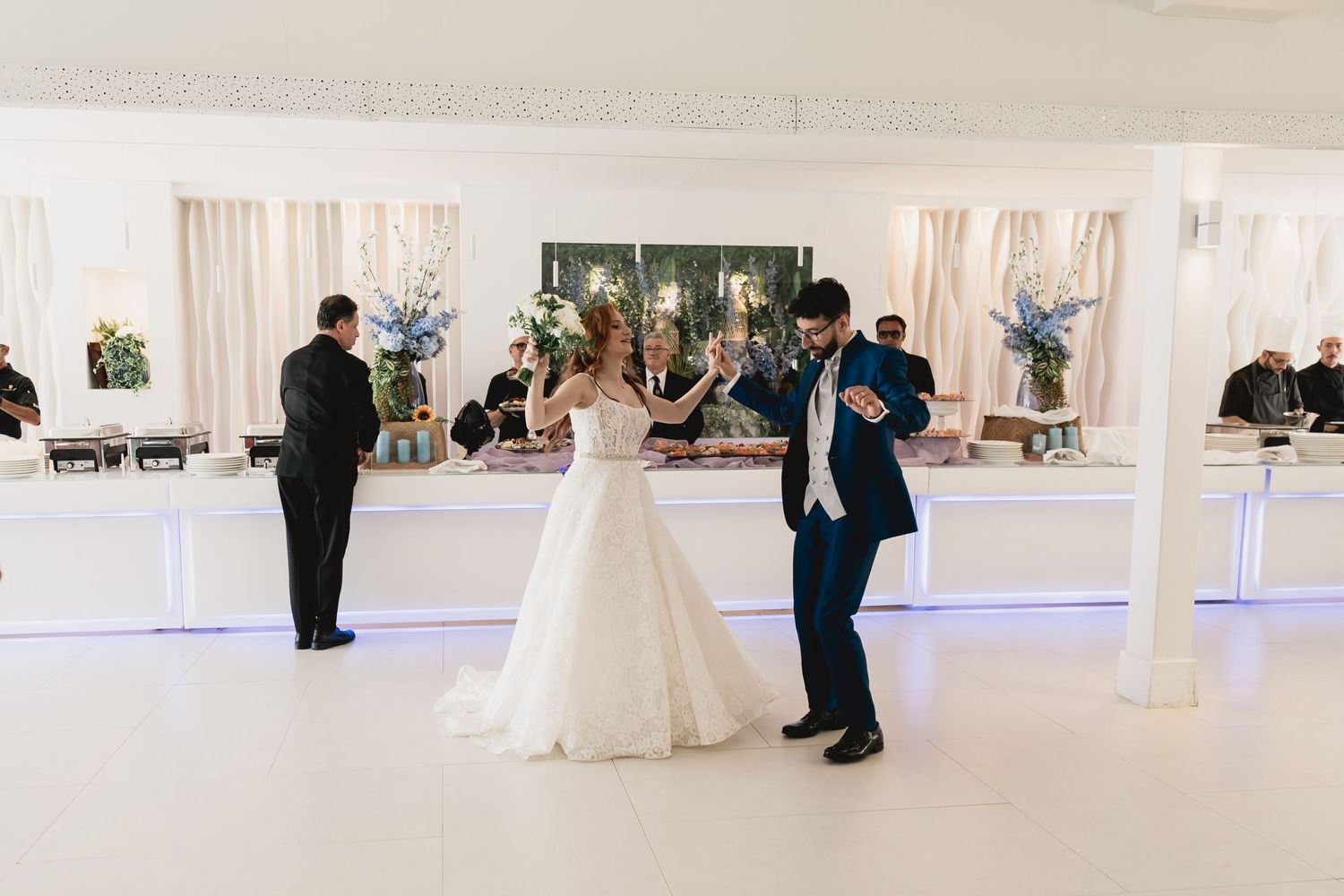 Elegant wedding reception scene in a white modern venue with decorative lighting.