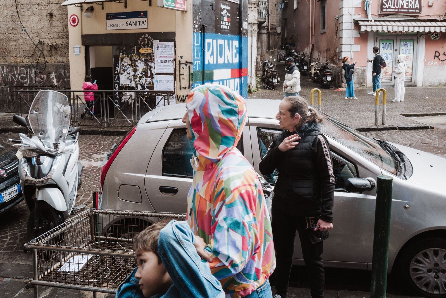 Street scene with colorful carnival costume next to parked cars in an urban setting.