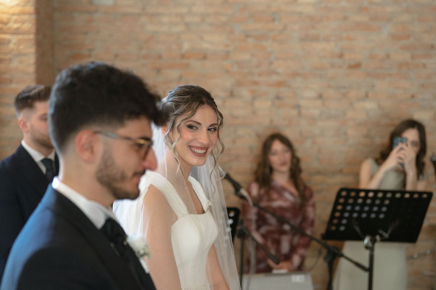 Couple sharing an emotional moment during wedding ceremony in a rustic brick venue.