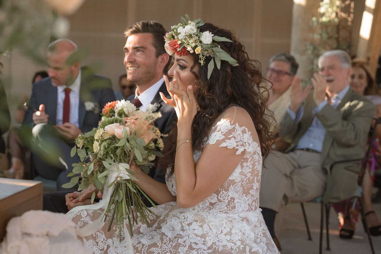 Emotional moment during wedding ceremony as bride holds bouquet of flowers.