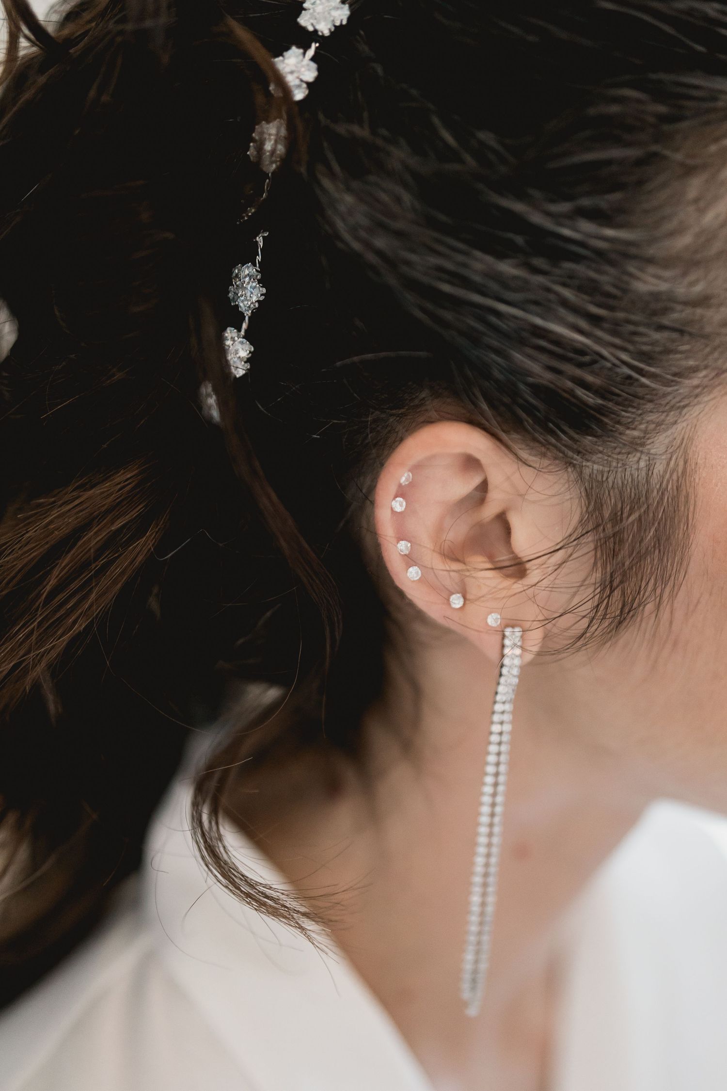 Elegant bridal earrings and hair accessories with multiple ear piercings shown in detail.
