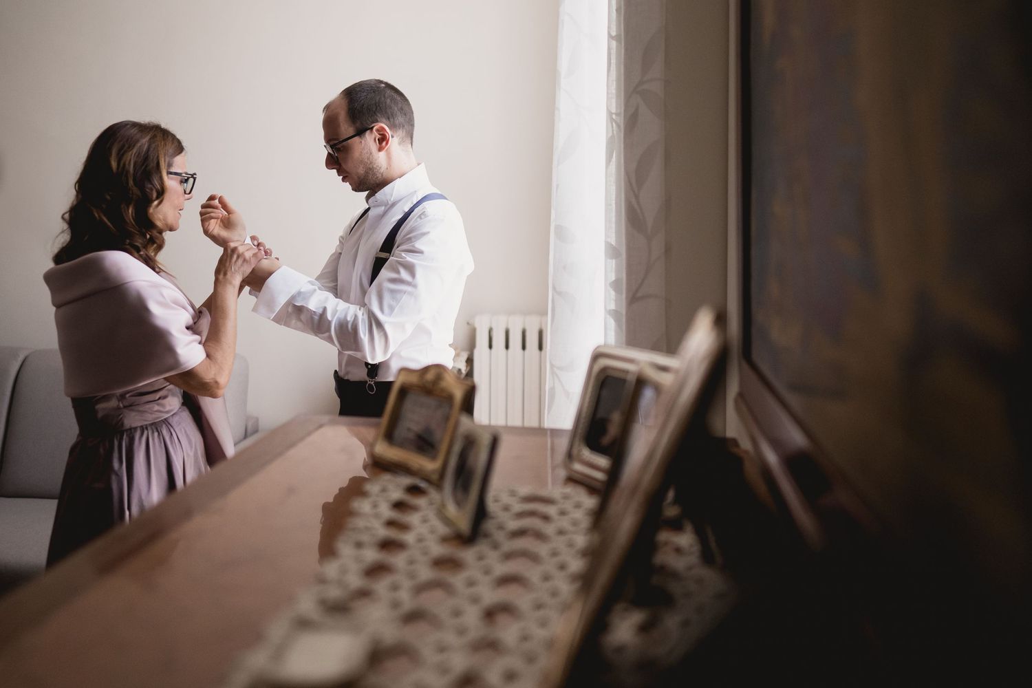Interior scene of couple getting ready by window with soft natural lighting.