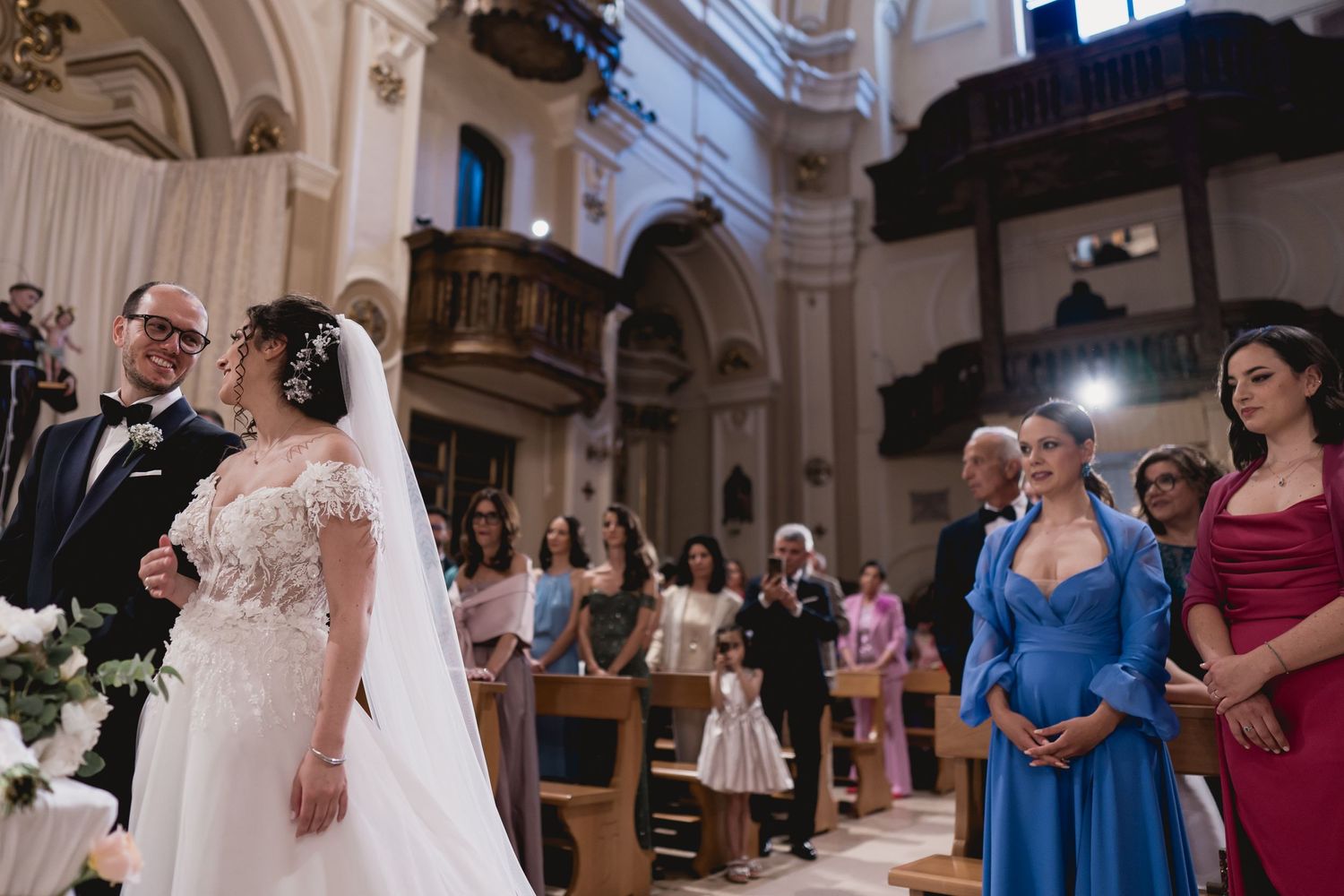 Traditional Catholic church wedding ceremony with guests watching the couple exchange vows at the altar.