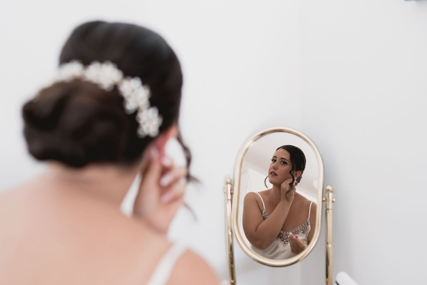 Bridal reflection in vintage vanity mirror with white floral hair accessory.