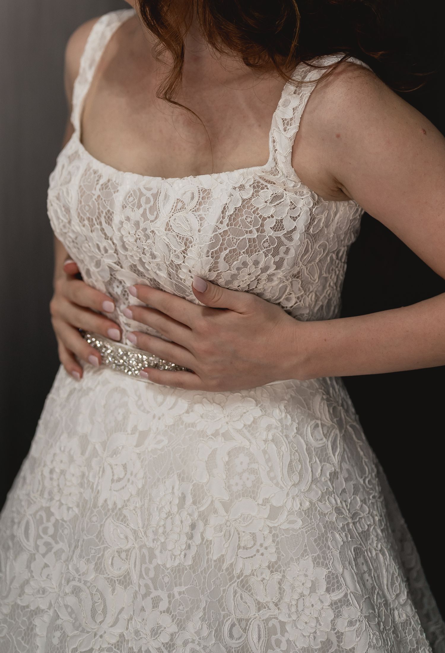 Close up detail of white lace bodice and crystal embellishments on a wedding dress.
