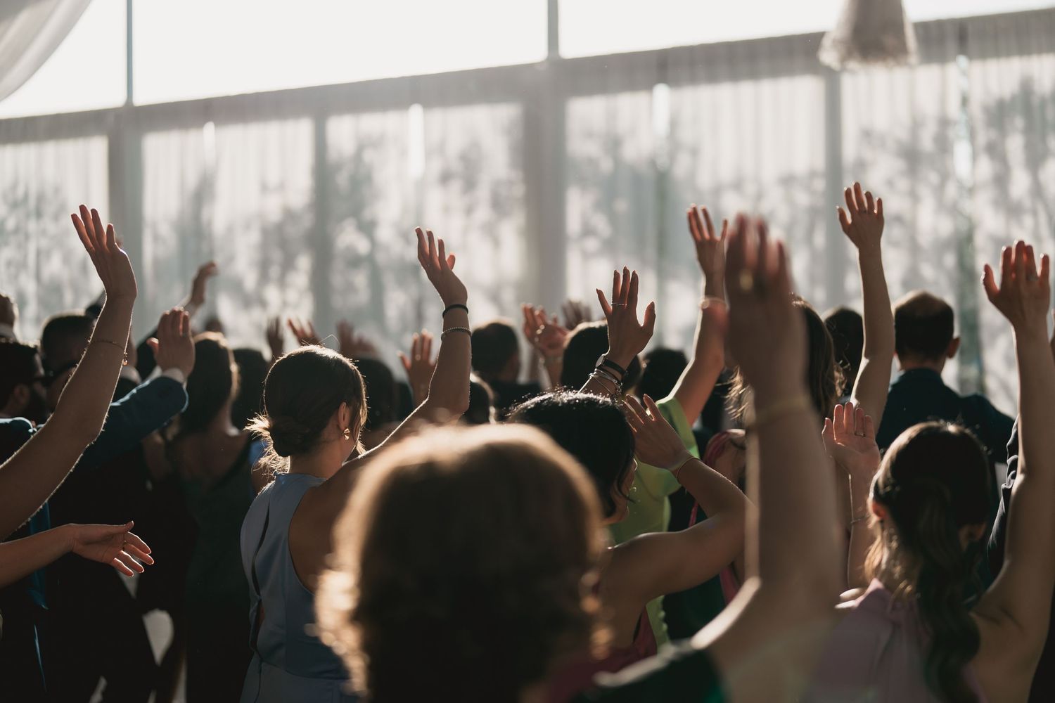 Wedding guests raise their hands in celebration during a joyful reception ceremony.