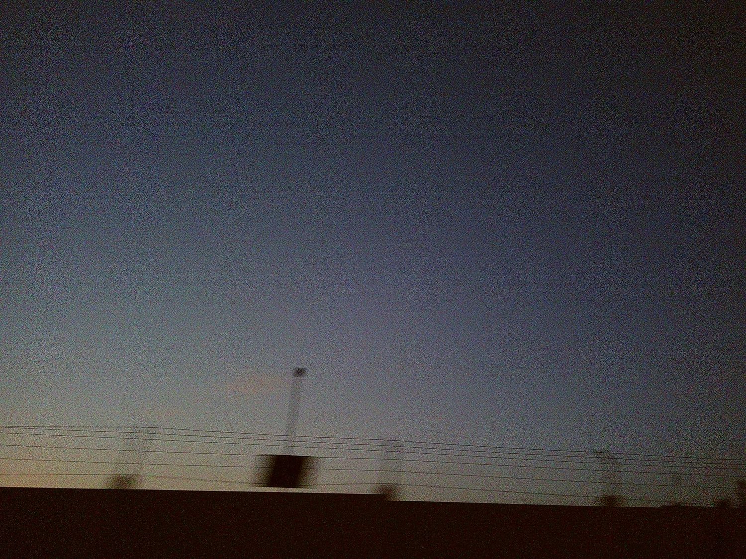 Power lines and poles silhouetted against a dusky evening sky.