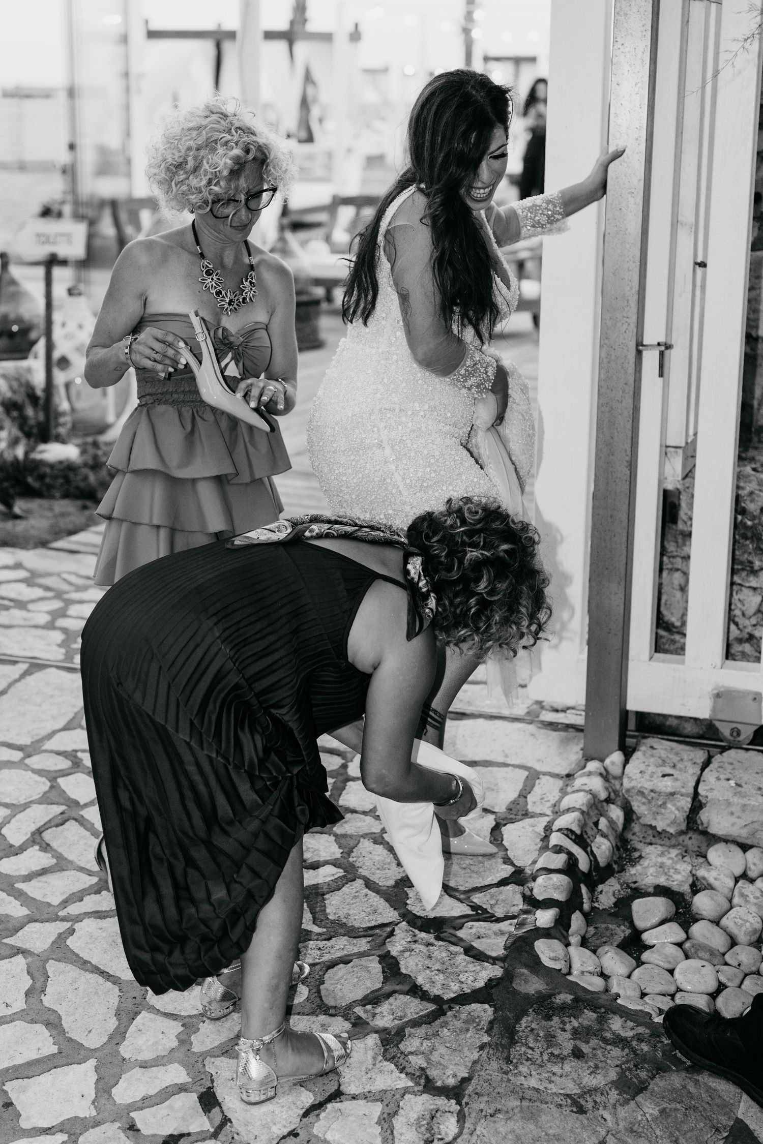 Black and white photo of people interacting on a stone patio with decorative railing.