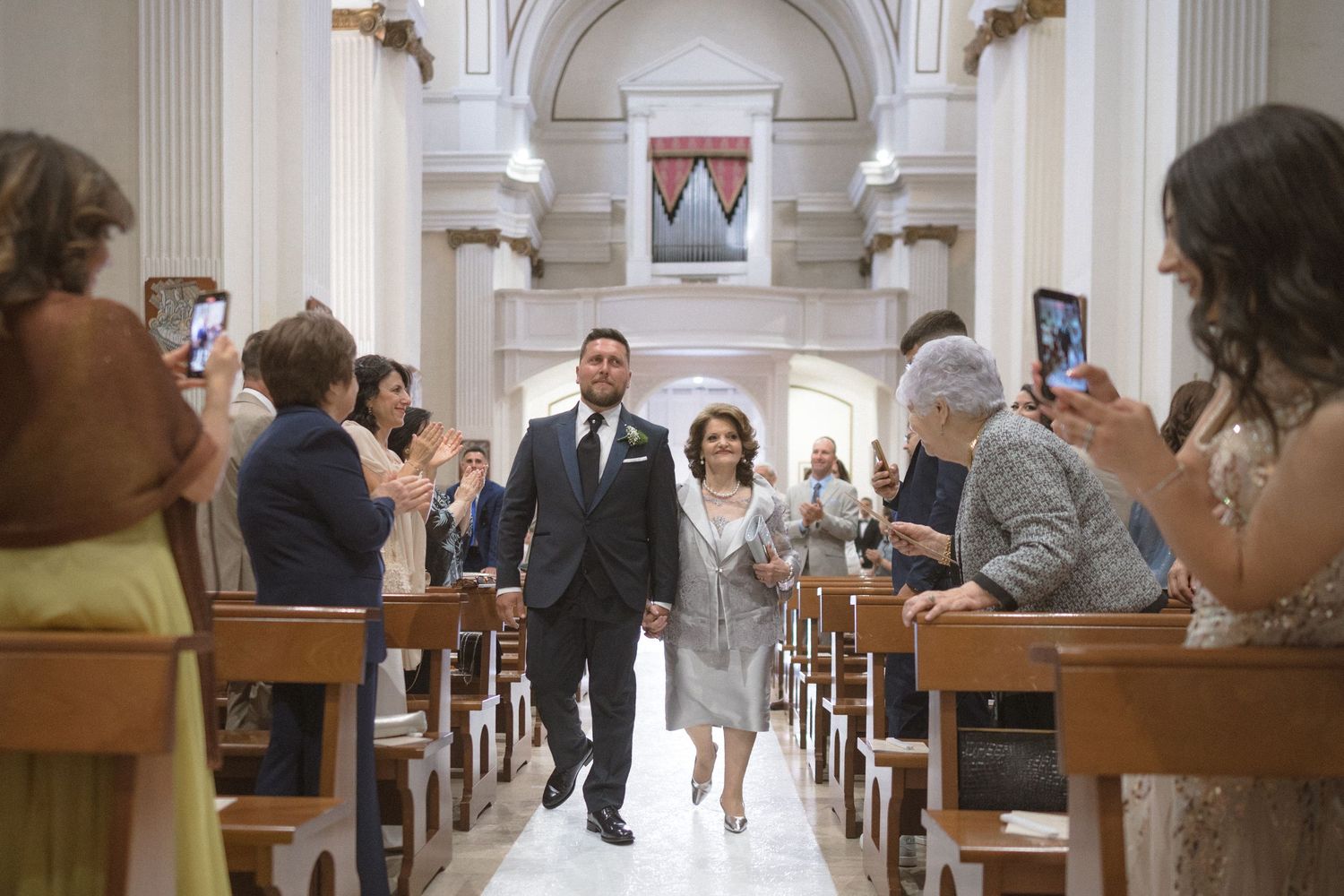 Traditional church wedding ceremony with white columns and wooden pews.