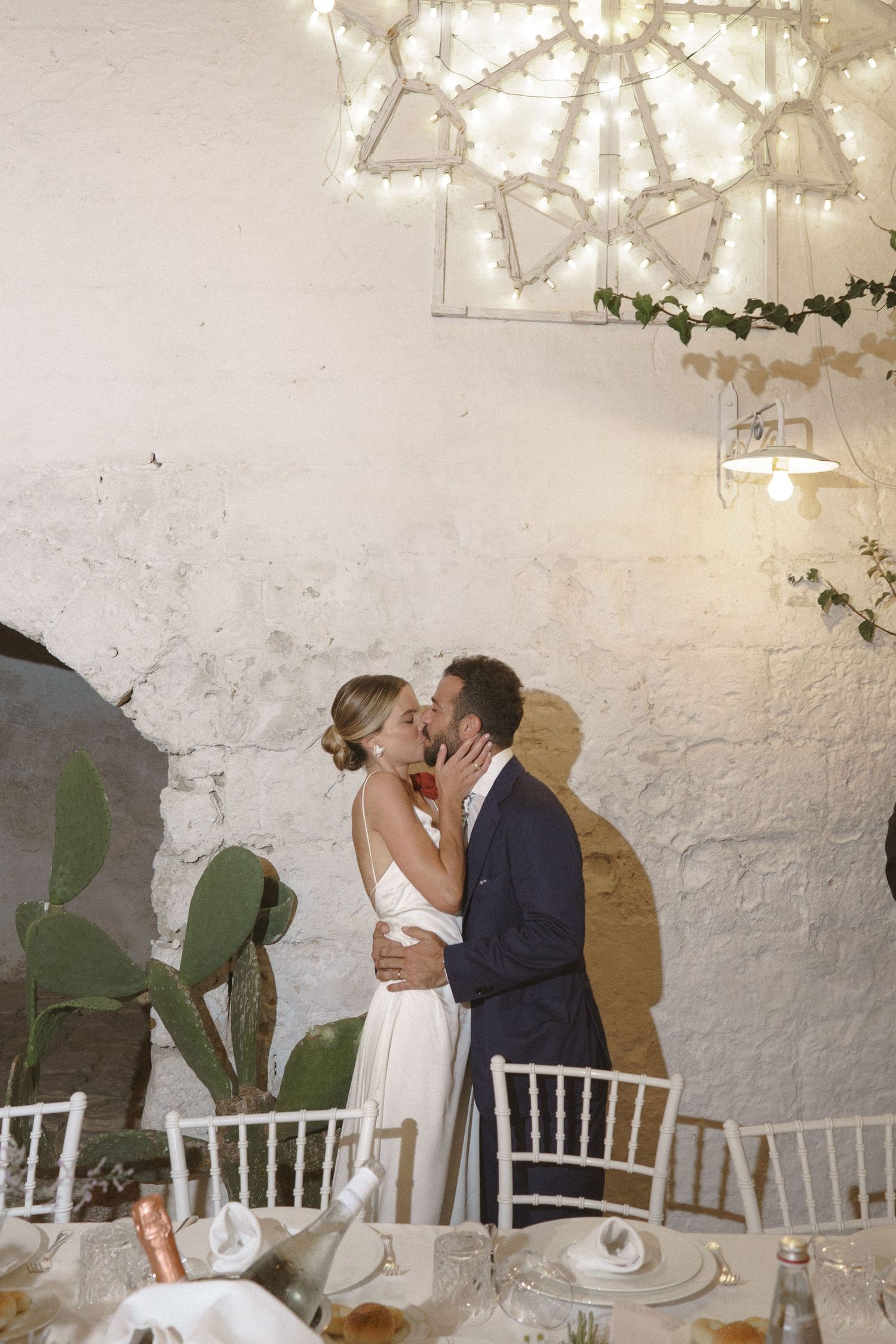 Romantic wedding reception moment under a decorative star light fixture against a white wall.