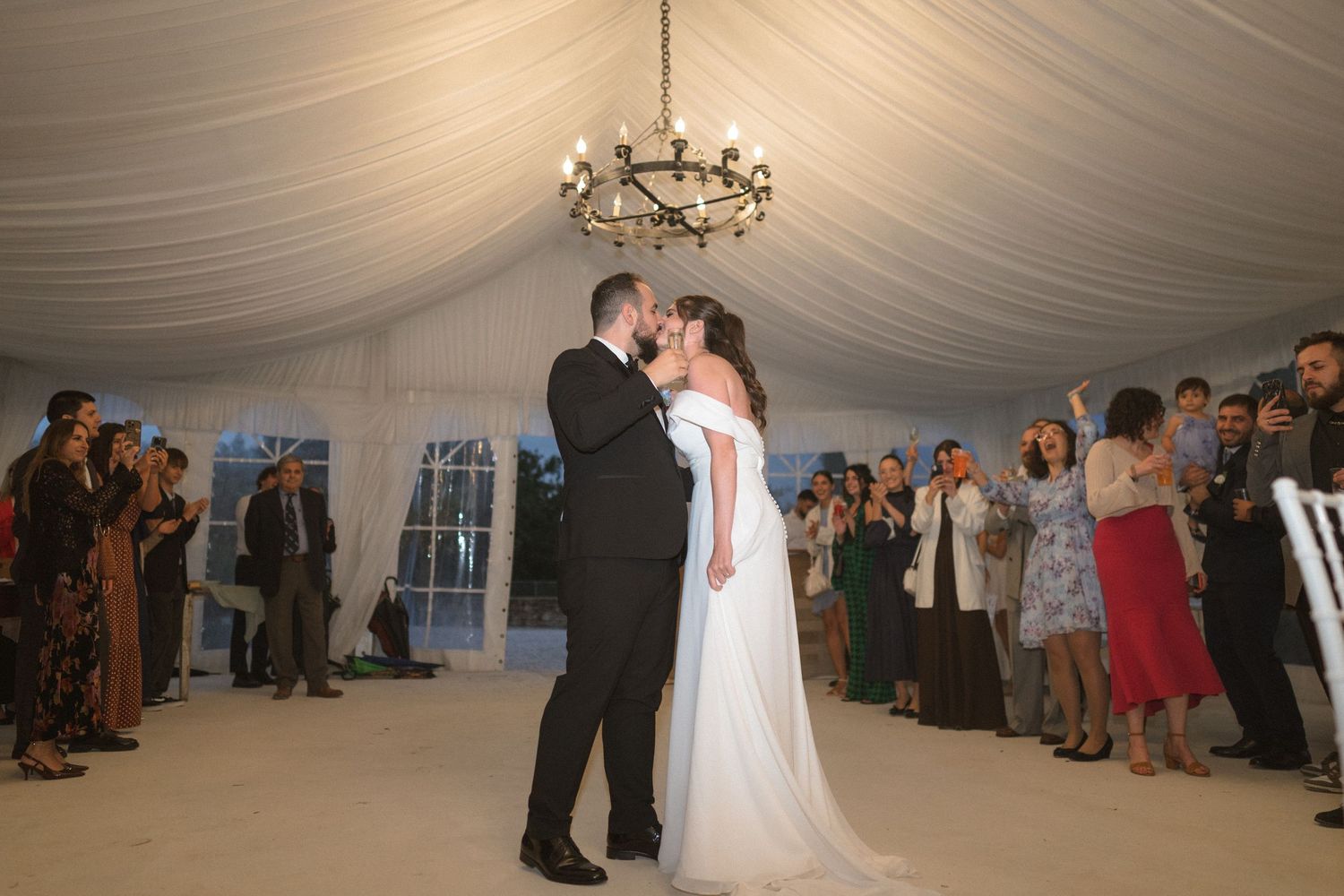 Couples dancing together on a white draped dance floor under elegant chandelier lighting.