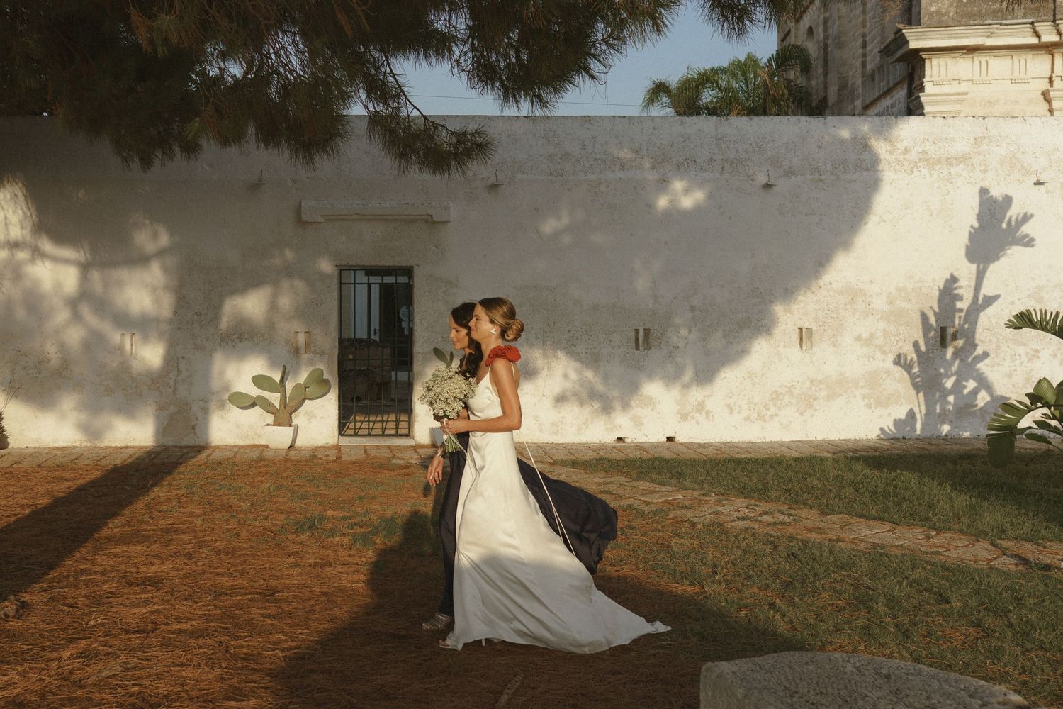 A romantic sunset moment at an outdoor venue with a white stone wall backdrop.