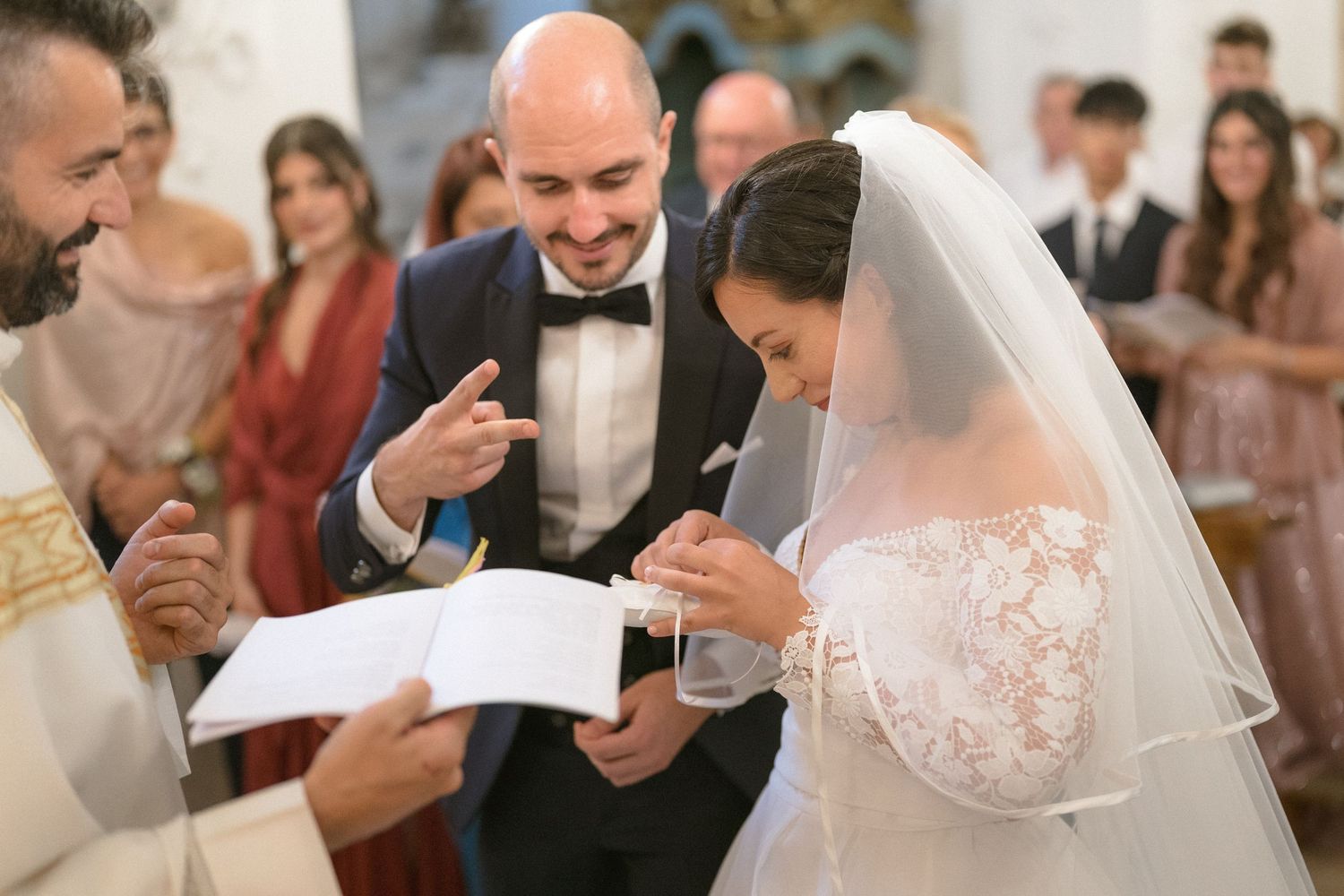 Wedding celebration scene with guests and newlyweds gathered around tables at an elegant reception.