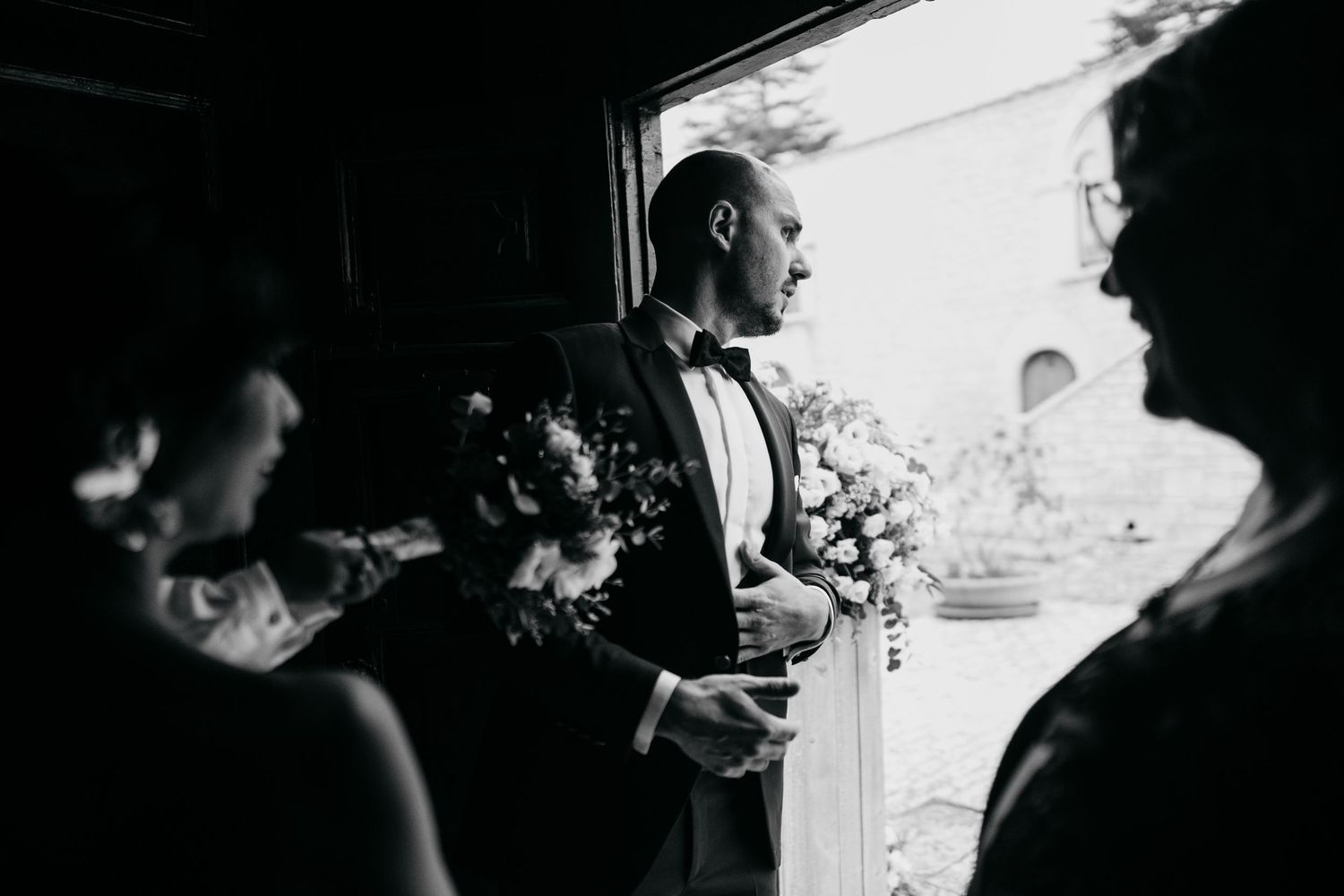 Silhouettes of wedding guests against bright window light.