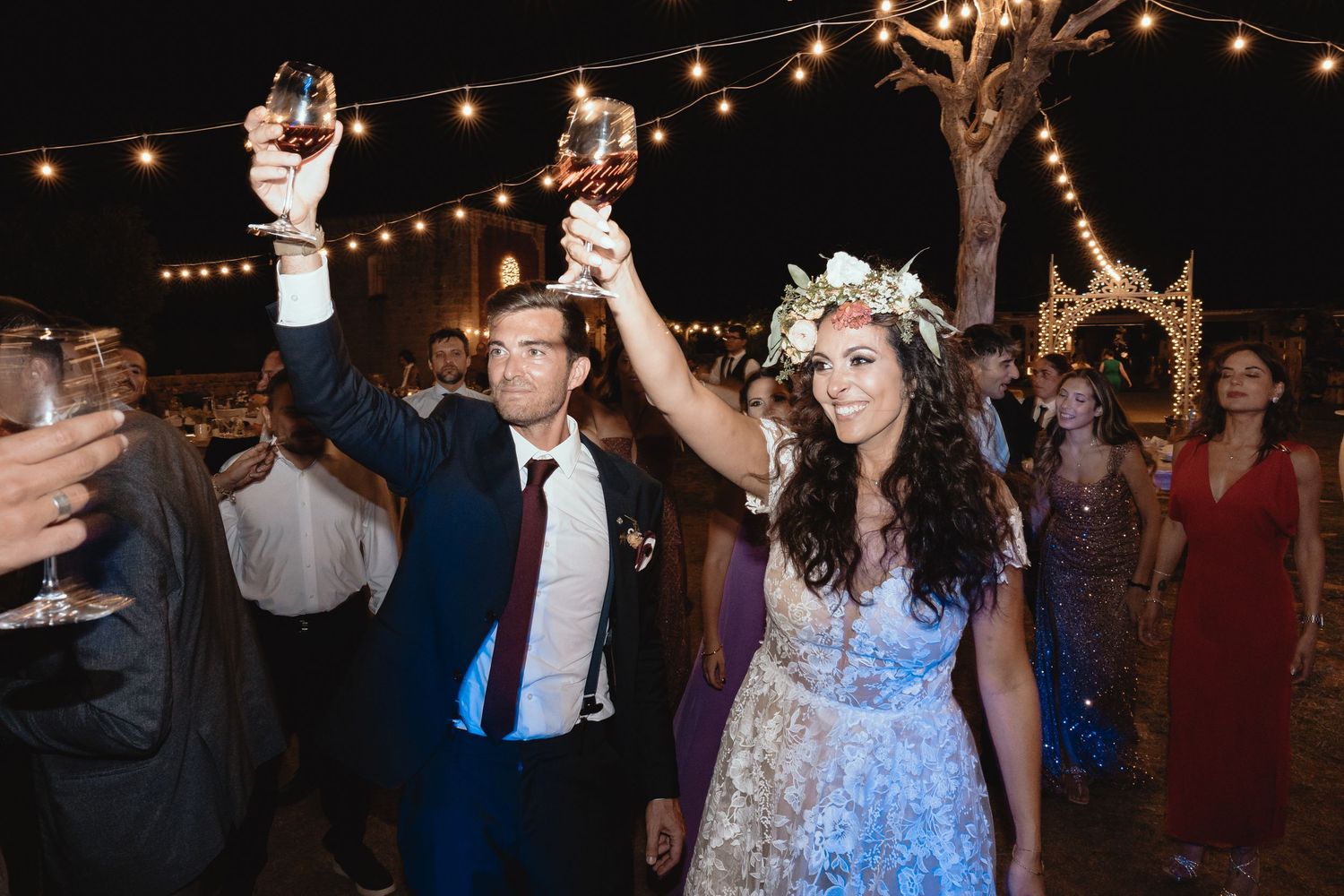 Wedding celebration at night with string lights illuminating guests dancing and socializing.