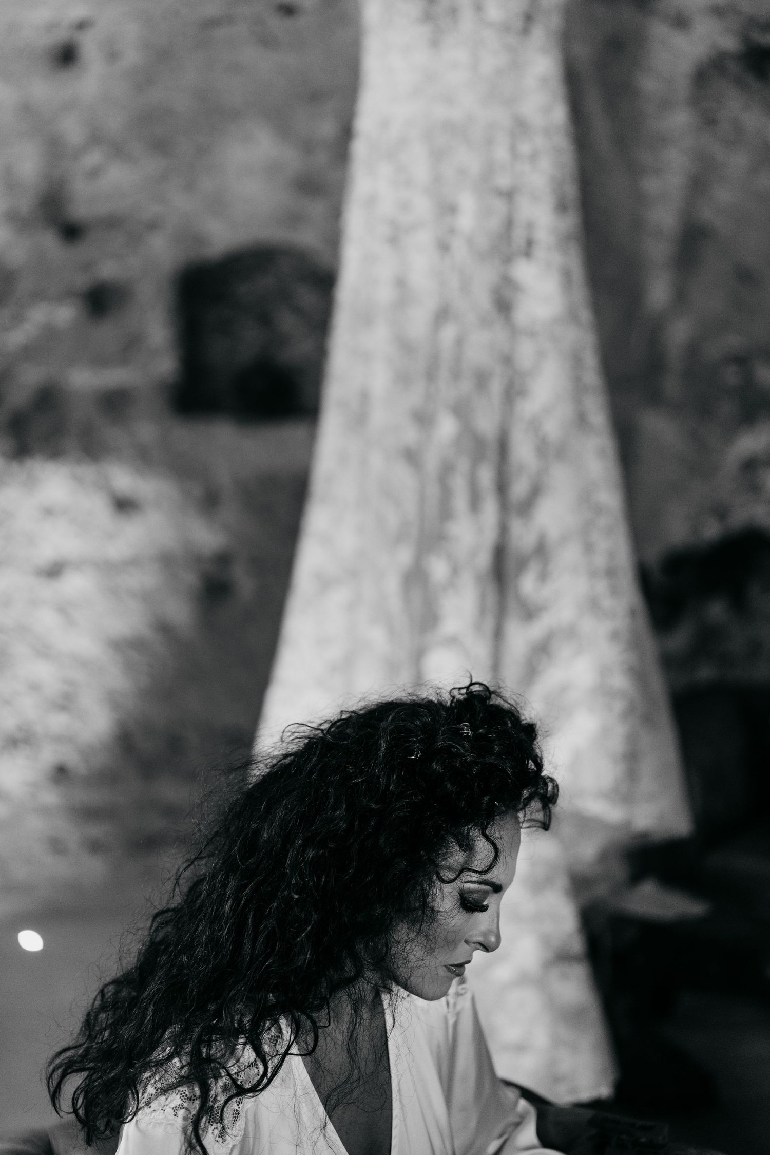 Black and white portrait showing dramatic side profile with flowing curls.