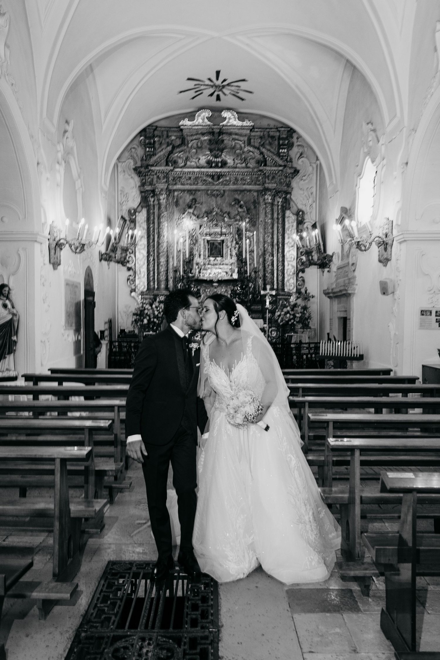 A couple share an intimate moment in a beautiful church aisle with ornate baroque altar in the background.
