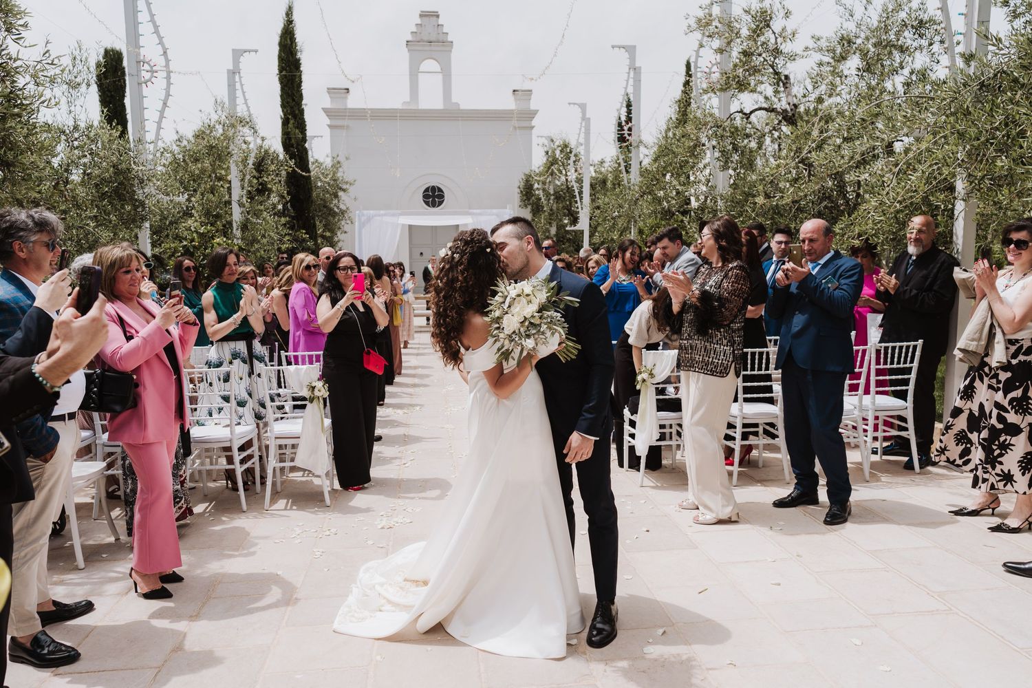 Wedding guests applaud as the newlyweds share their first dance on an outdoor patio.