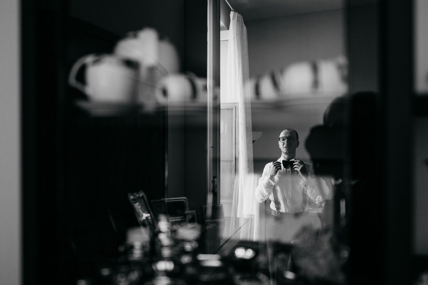 A black and white reflection shot of formal attire preparations in a vintage-style room.