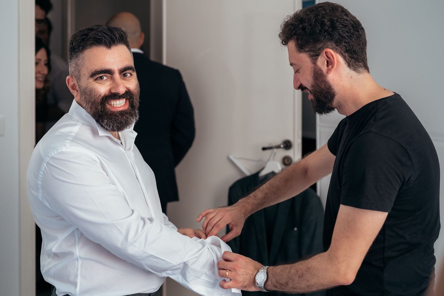 Two people helping with formal shirt preparation.