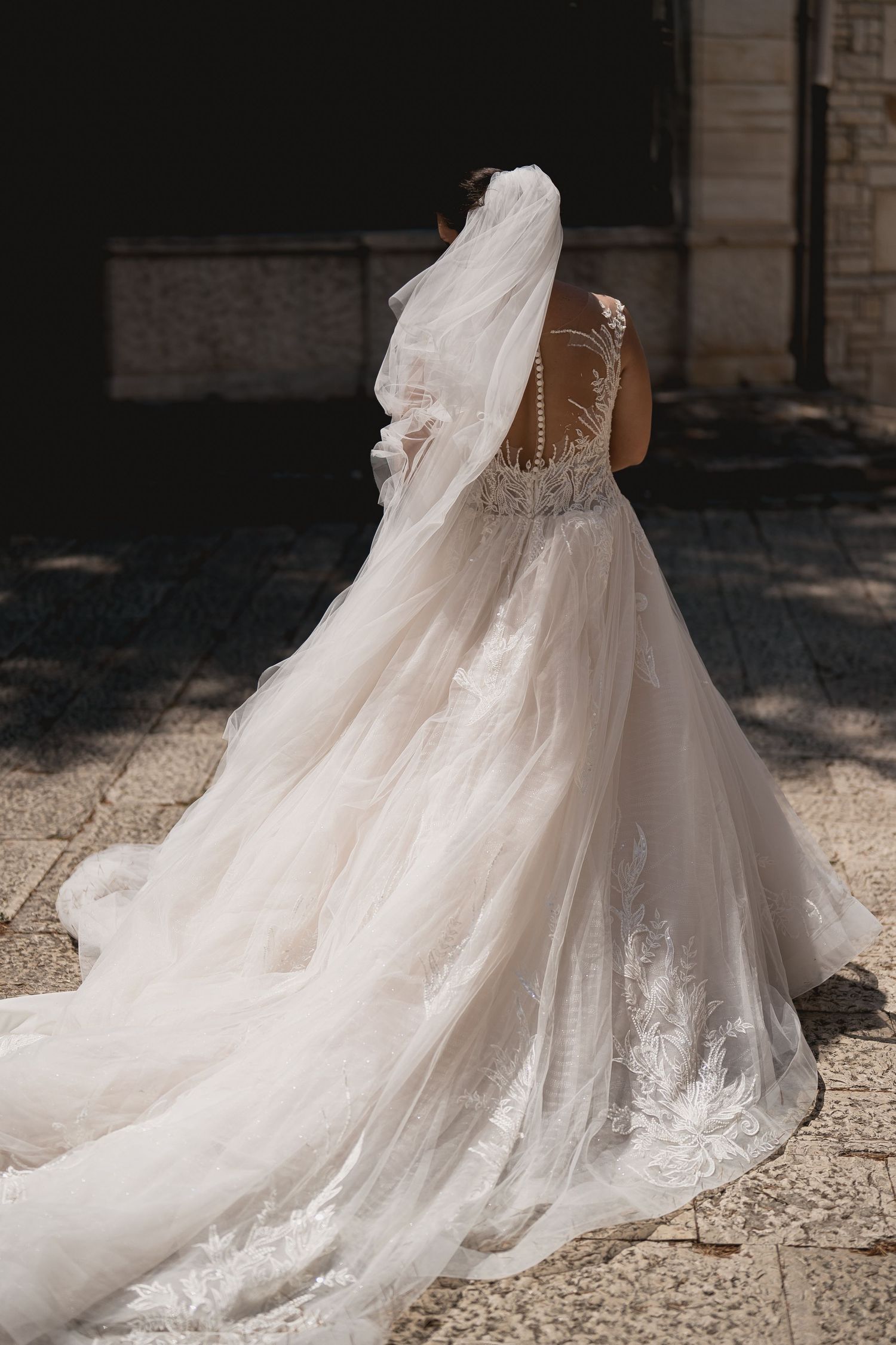 Back view of an elegant lace wedding gown with long flowing train.