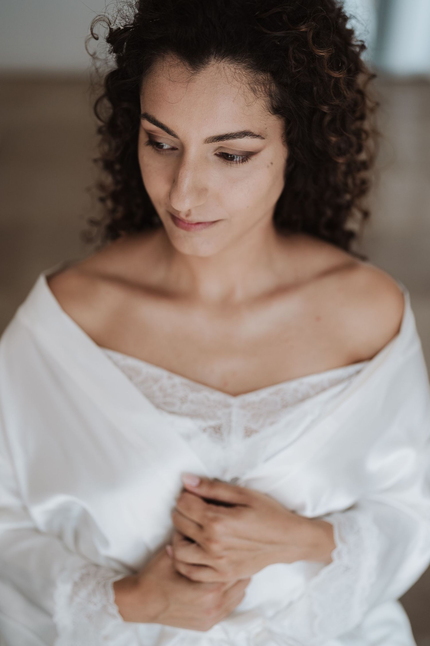 Serene portrait of a person in white off-shoulder attire with natural curly hair.
