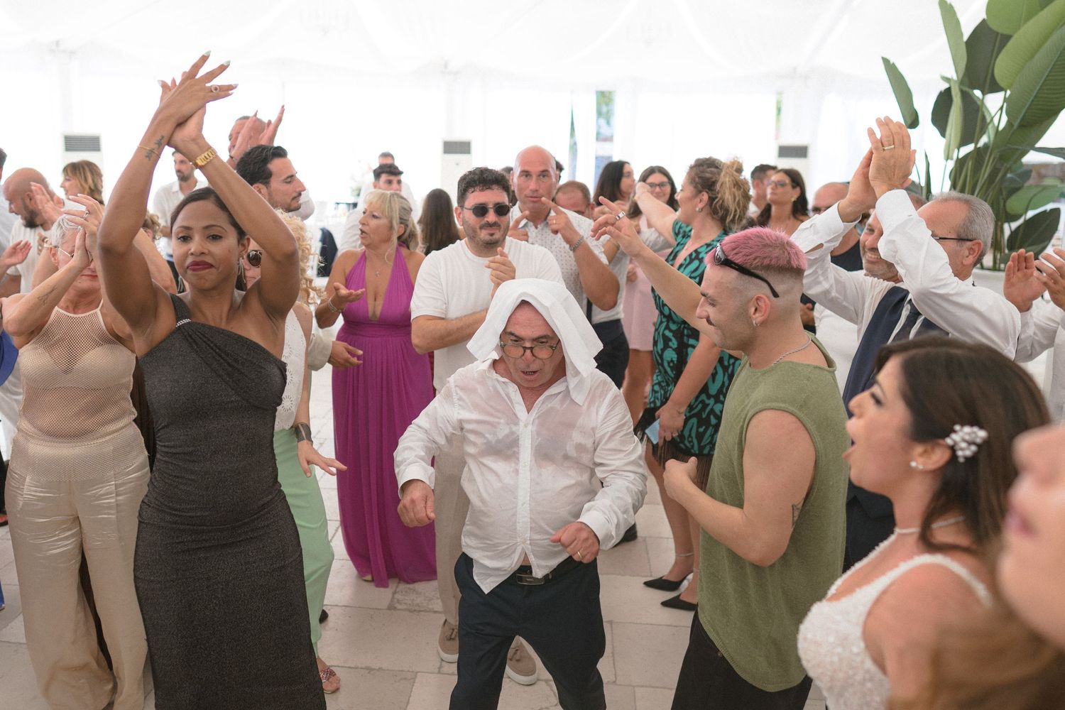 Wedding guests dancing and celebrating on dance floor at reception.