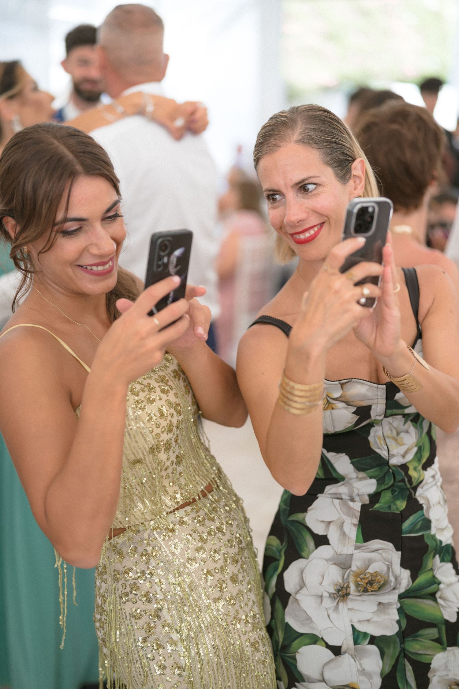 Wedding guests in formal attire taking photos with smartphones during celebration.