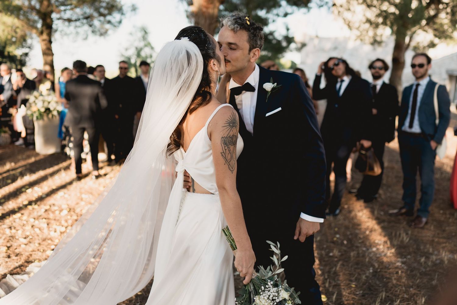 A romantic sunset wedding ceremony outdoors with pine trees and golden light illuminating the intimate moment.