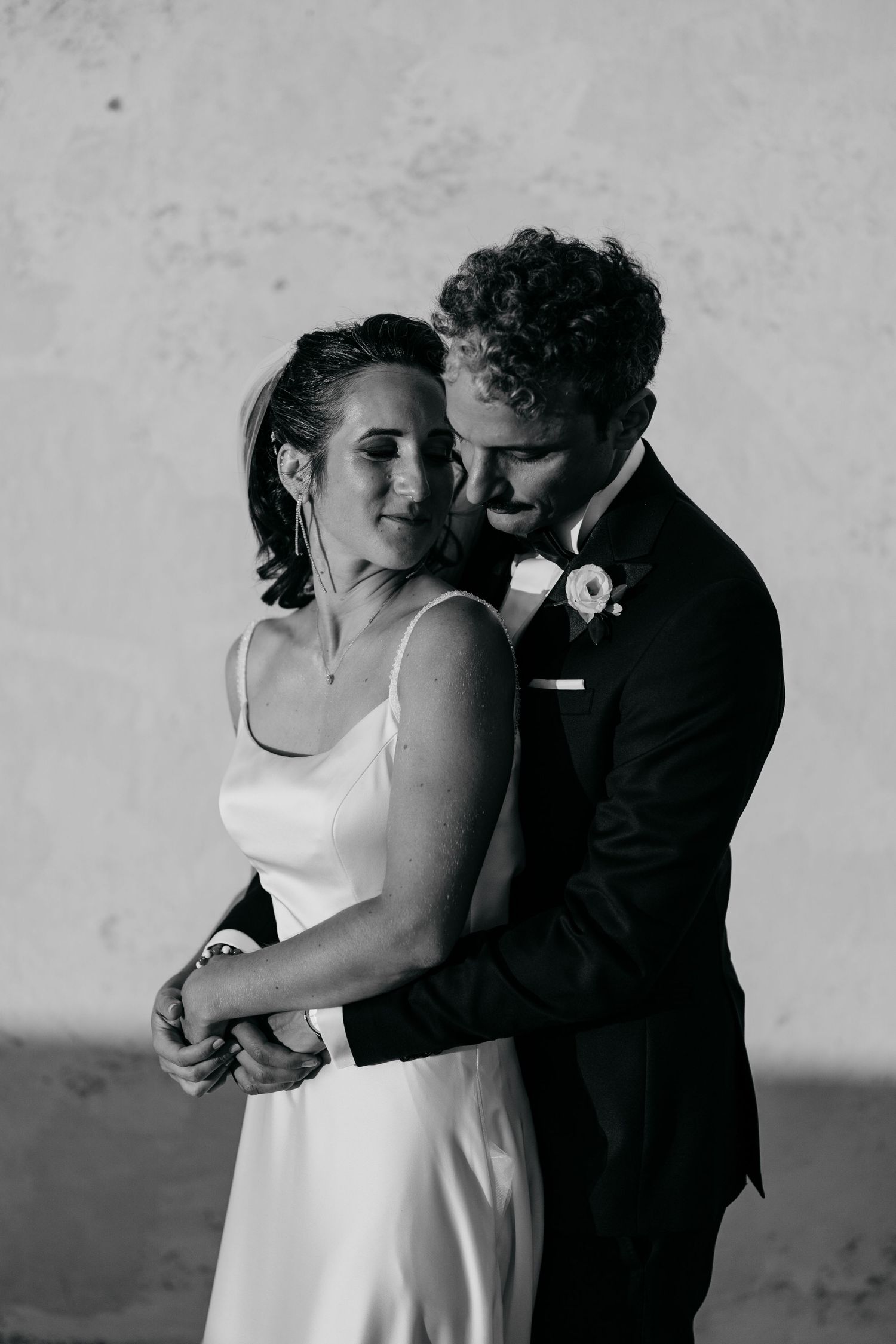 A romantic black and white portrait of a couple sharing an intimate moment in wedding attire.