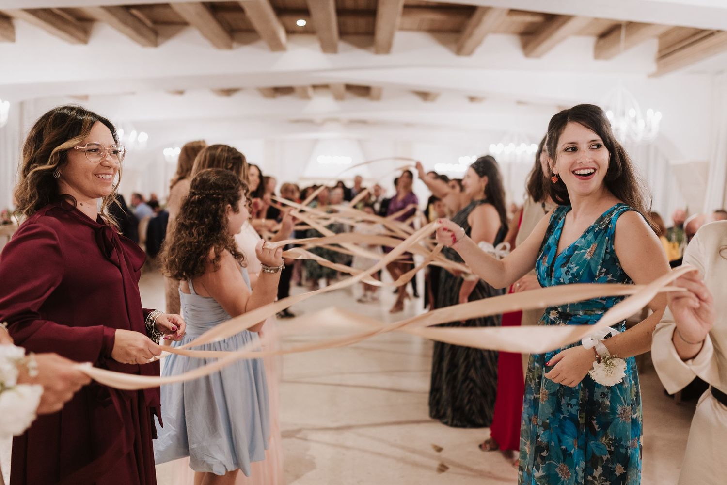 Wedding guests dancing and celebrating in a bright indoor reception venue.