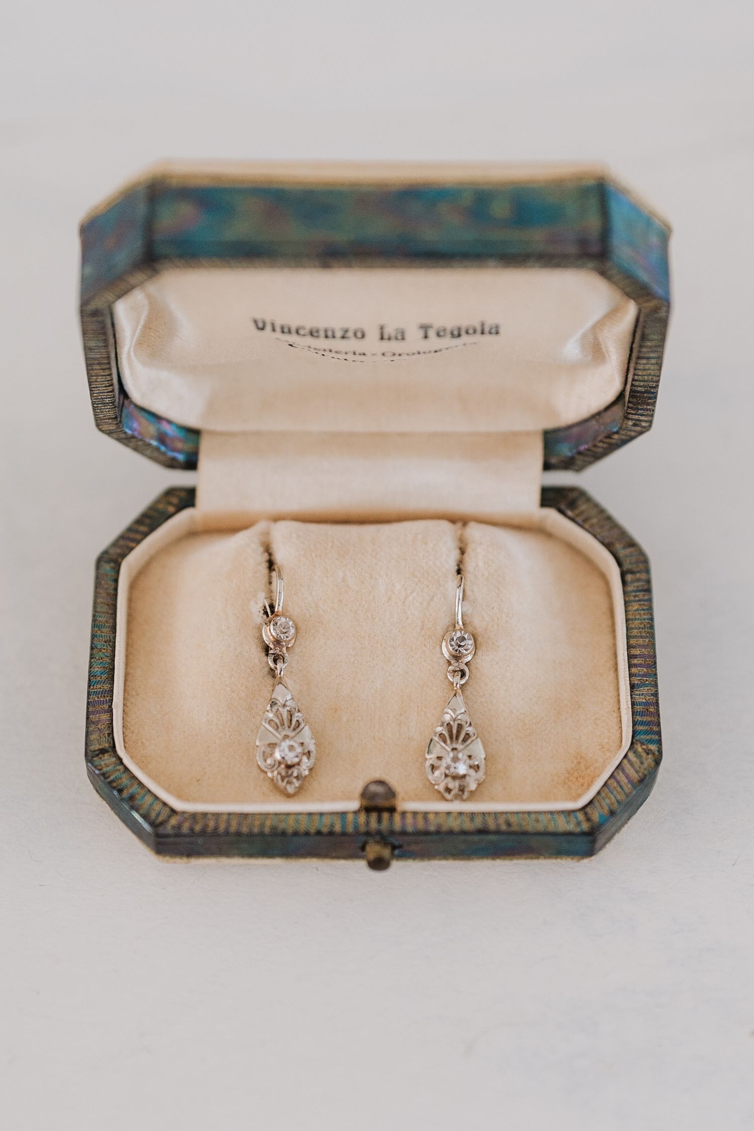 Vintage jewelry box containing delicate crystal drop earrings with Vincenzo La Tenda branding.