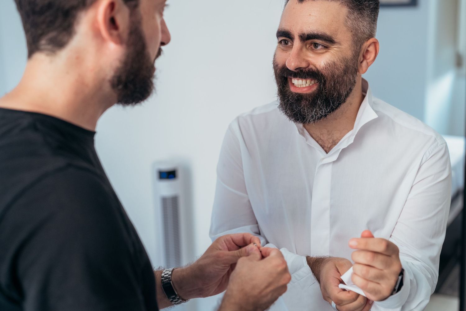 Two people engaged in conversation while preparing formal attire.