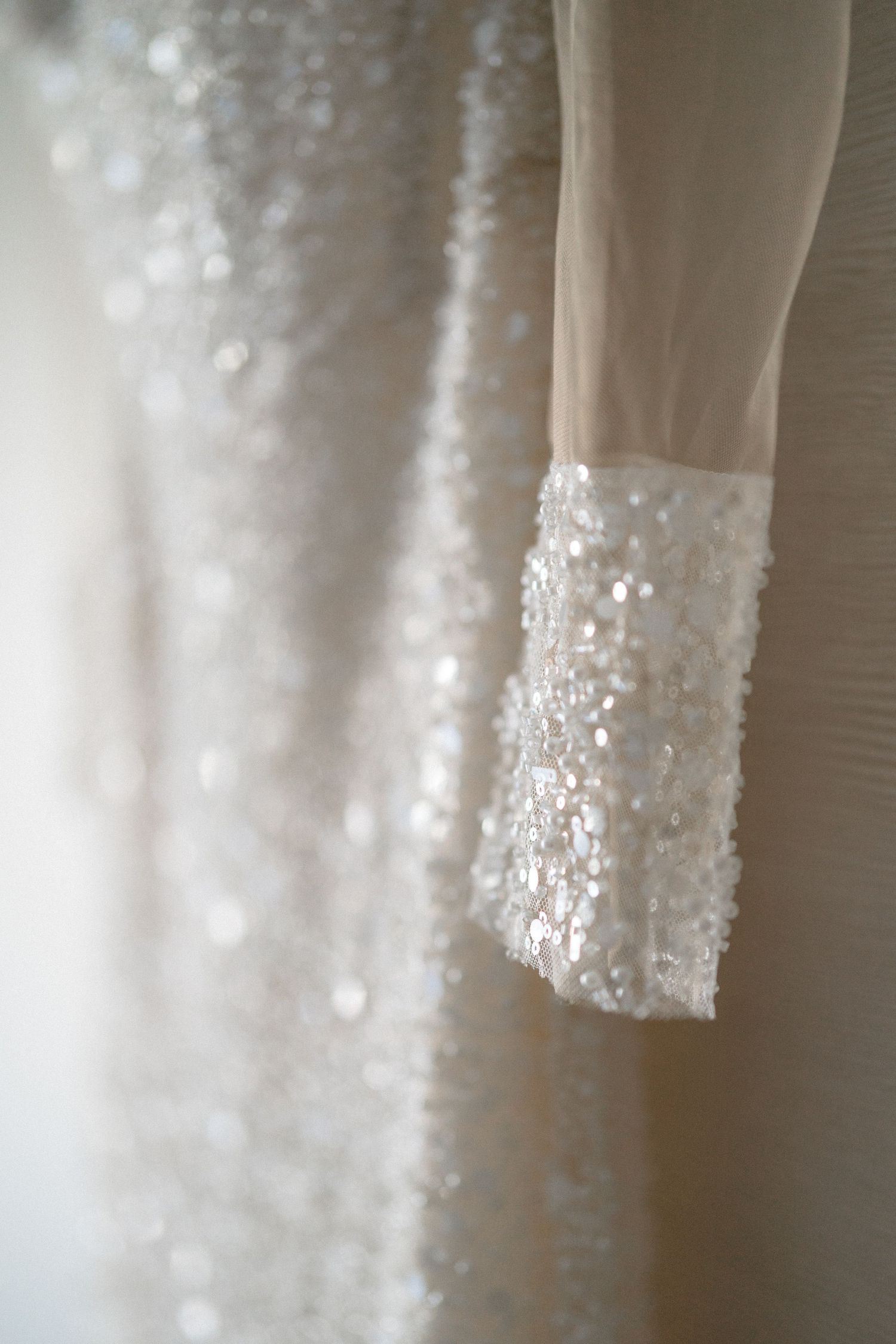 Close-up detail of delicate beading and sequins on white fabric.
