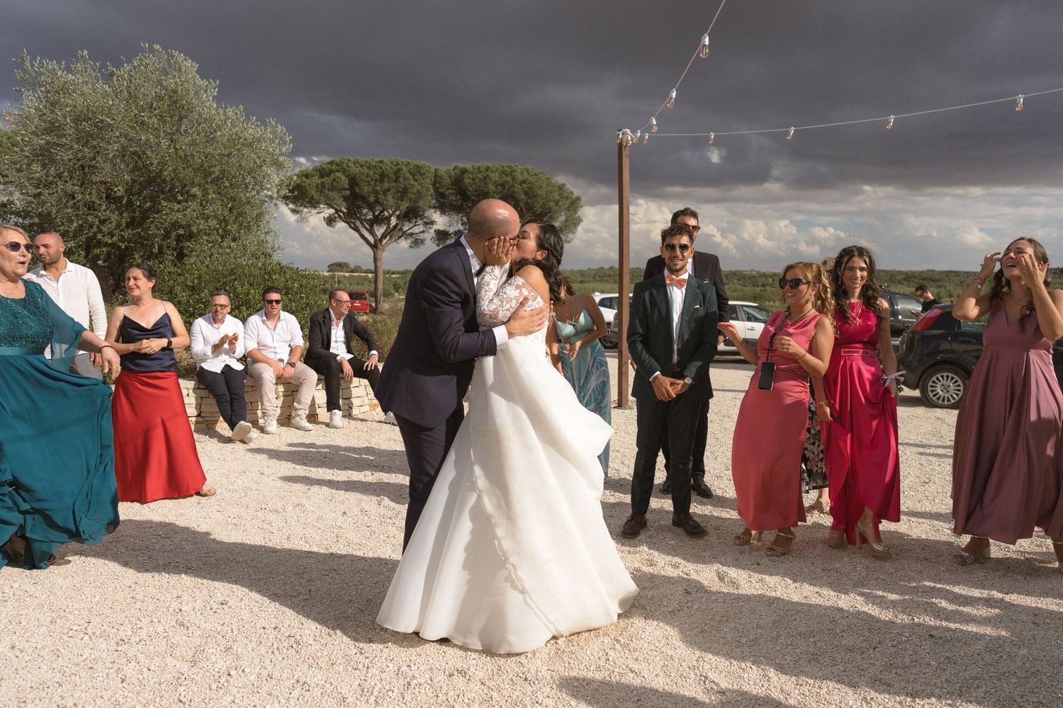 Wedding guests gathered outdoors under dramatic stormy sky.