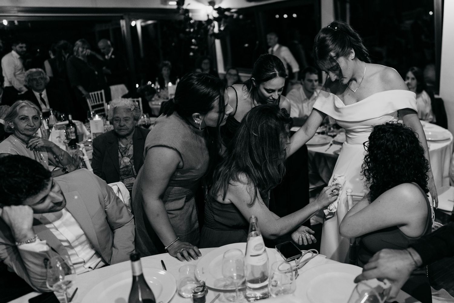 Black and white photo of wedding reception guests gathered around dining tables.