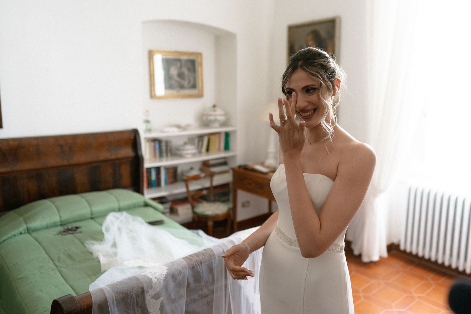 A bride getting ready in a bright white room with elegant details and natural lighting.